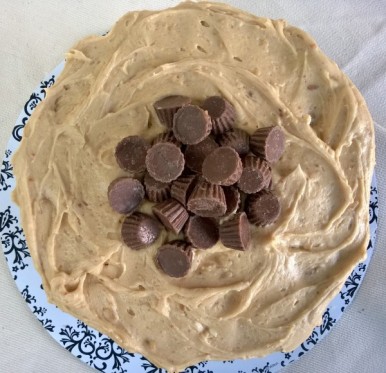 Reese's peanut butter cups mounded in the center of the peanut butter frosting, gracing 3 layers of chocolate cake.